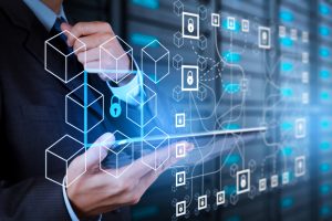 Businessman holds tablet computer, digital icons of encrypted blocks illustrating distributed ledger technology.
