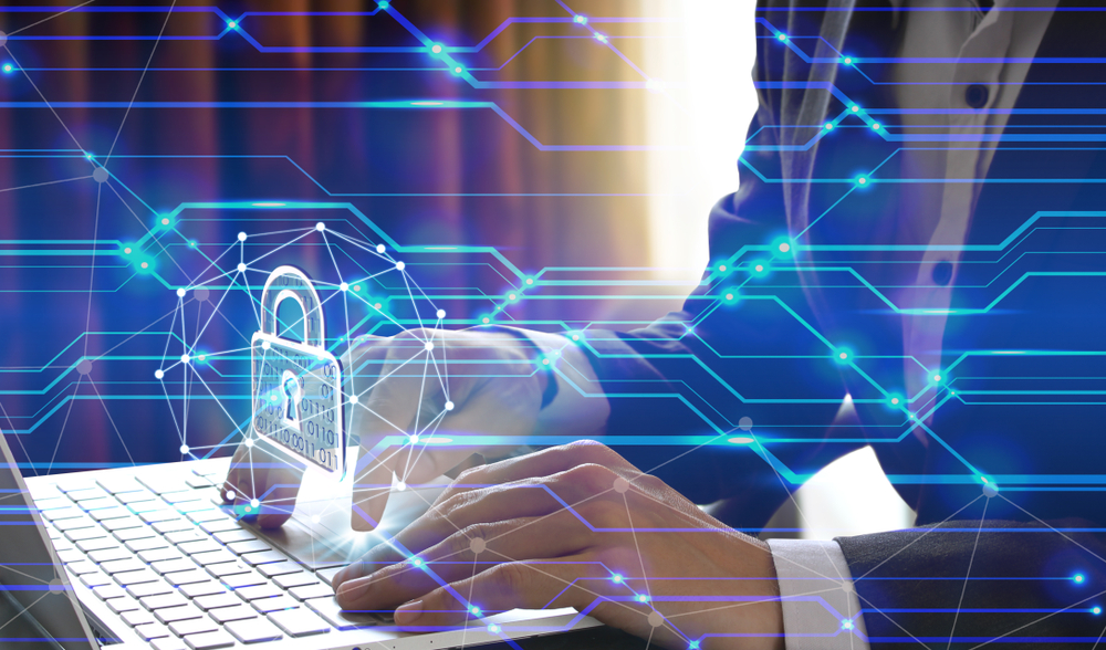 Businessman types on laptop computer, overlaid with digital lines and padlock icon to illustrate preventing third-party breaches.